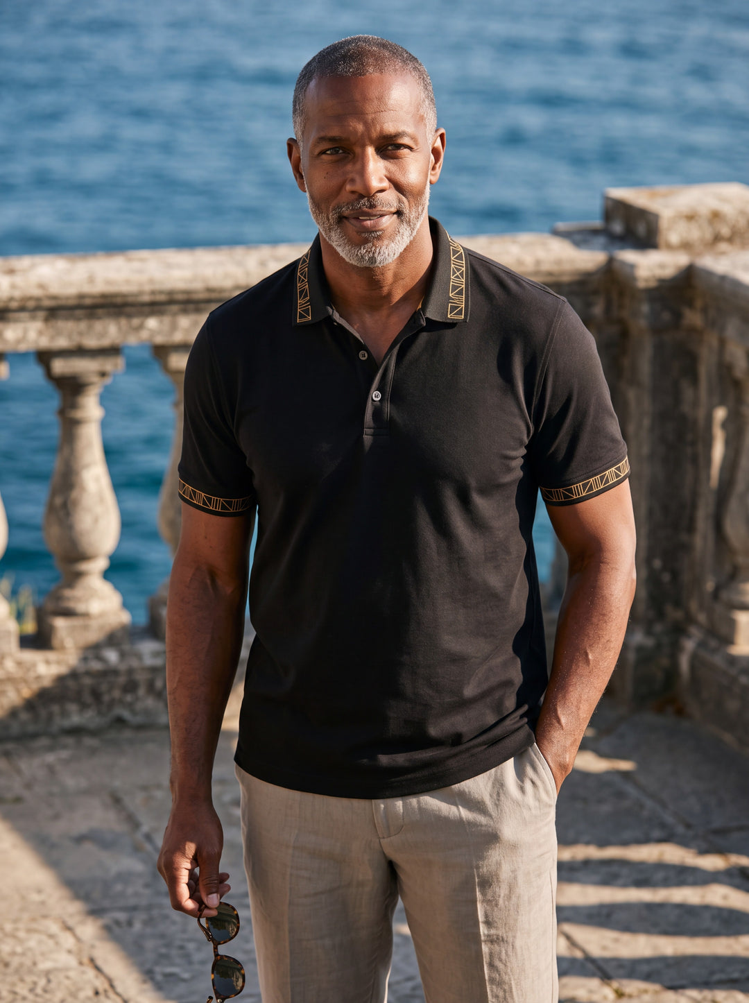 Arthur Men polo shirt in black, worn by a model on a Mediterranean terrace - Gentlemens Manor lifestyle
