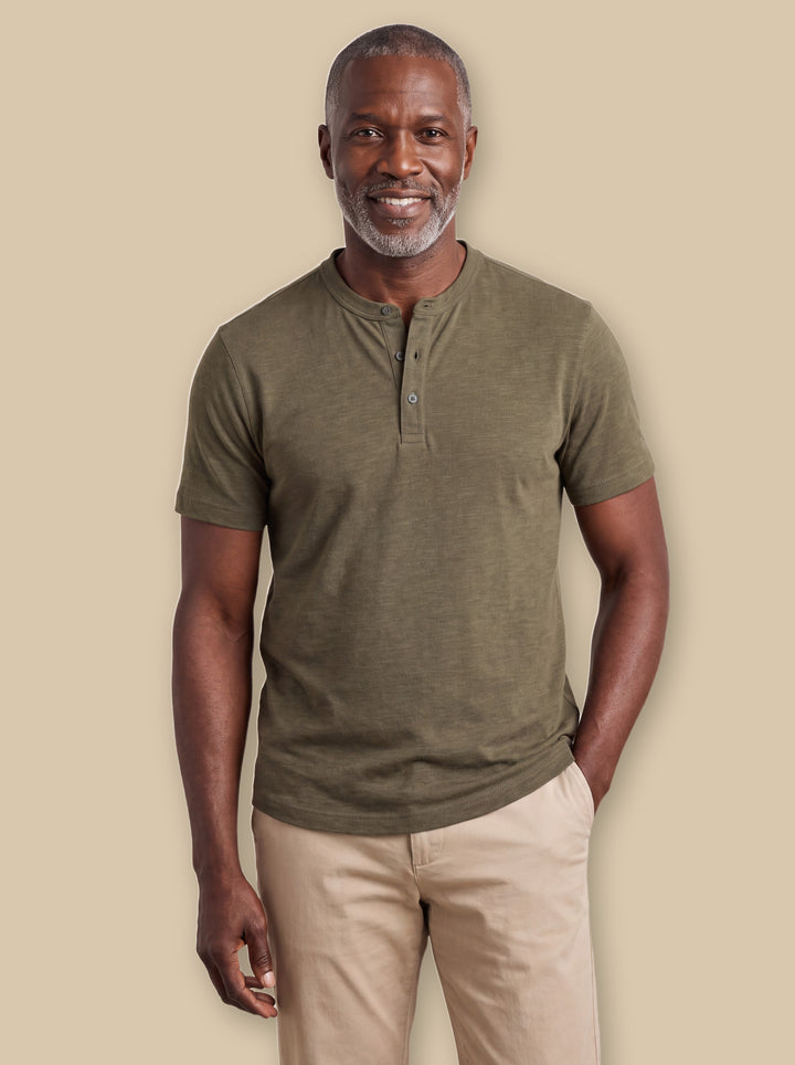 Basil polo shirt in Olive, worn by a model on a warm sand studio background - Gentlemens Manor