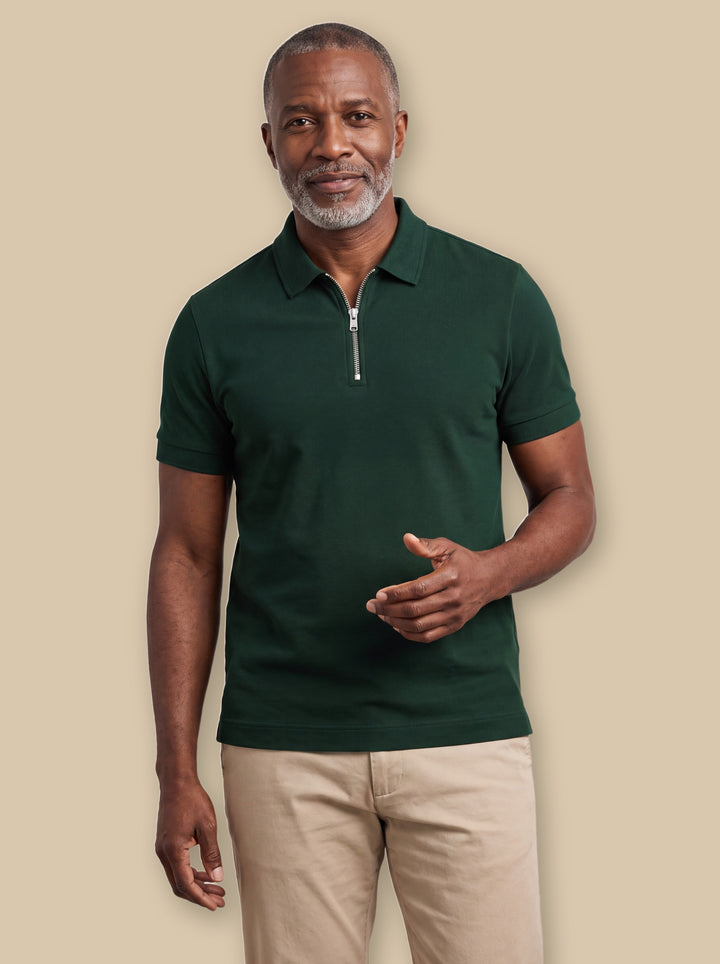 Baxter polo shirt in Green, worn by a model on a warm sand studio background - Gentlemens Manor