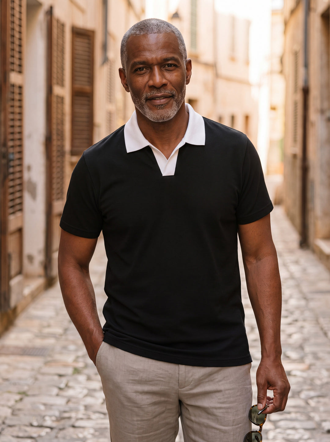 Booker Men polo shirt in black, worn by a model on a Mediterranean terrace - Gentlemens Manor lifestyle