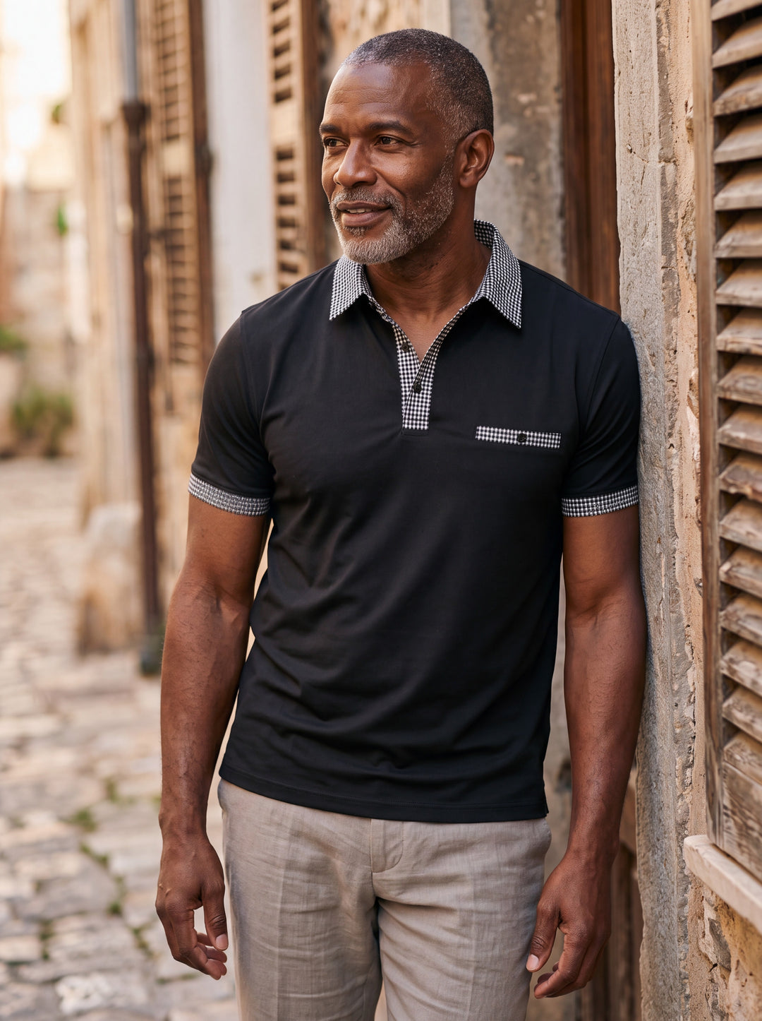 Boone Men polo shirt in black, worn by a model on a Mediterranean terrace - Gentlemens Manor lifestyle