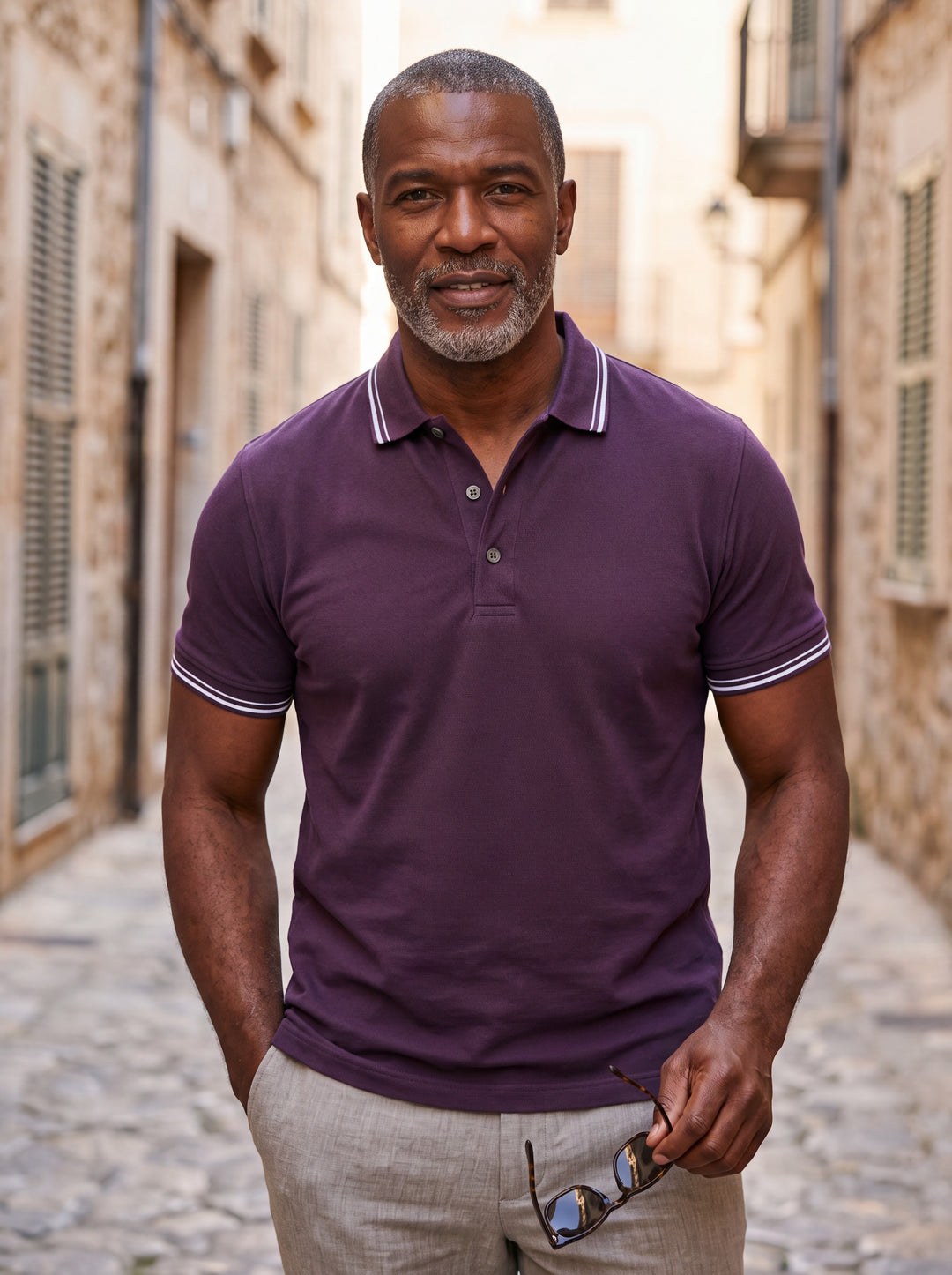 Carlton Men polo shirt in purple, worn by a model on a Mediterranean terrace - Gentlemens Manor lifestyle