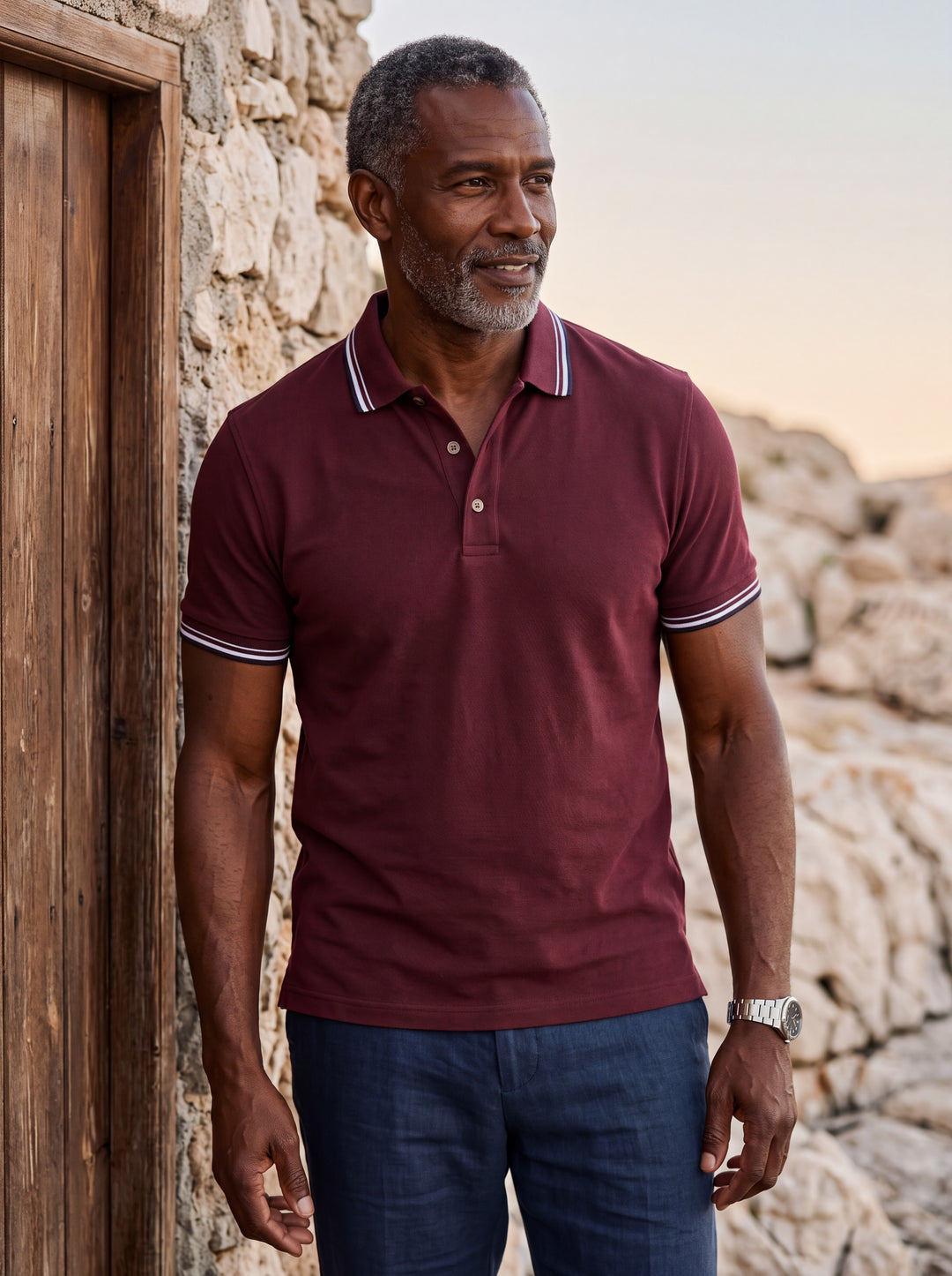 Carlton Men polo shirt in Burgundy, worn by a model on a Mediterranean terrace - Gentlemens Manor lifestyle