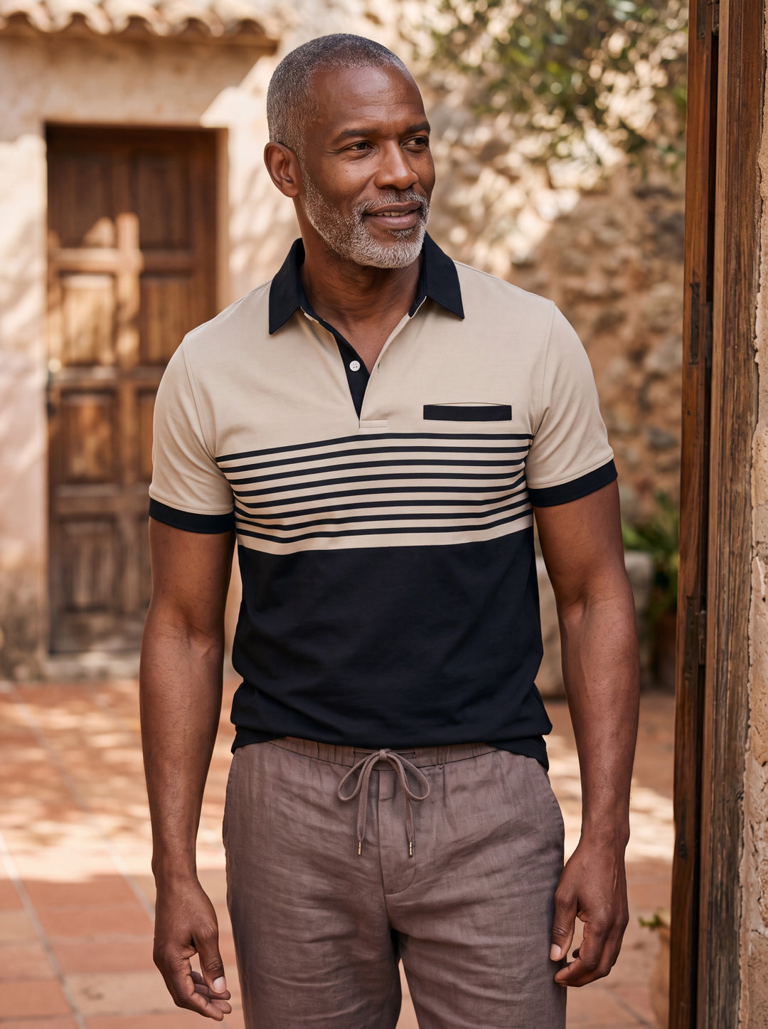 Crawford Men polo shirt in sand, worn by a model on a Mediterranean terrace - Gentlemens Manor lifestyle