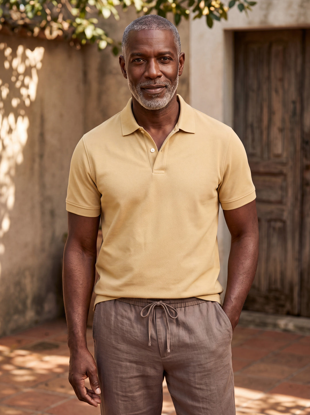 Dudley Men polo shirt in Mustard, worn by a model on a Mediterranean terrace - Gentlemens Manor lifestyle