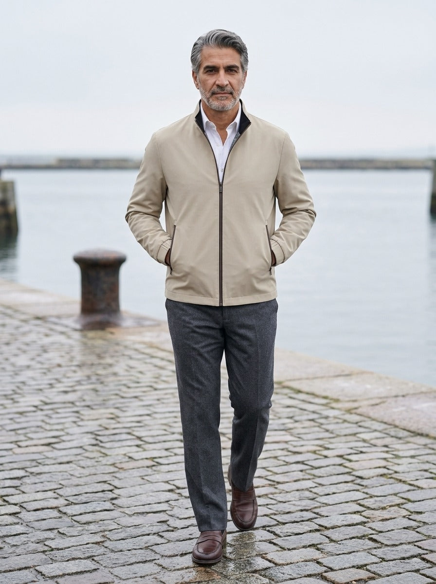 Elliot lightweight stand collar jacket in Sand, lifestyle on a stone harbor quay, Gentlemens Manor