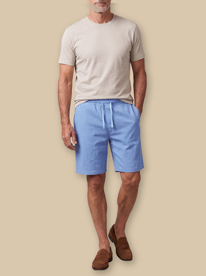 Lewis summer shorts in Blue, worn by a model on a warm sand studio background - Gentlemens Manor