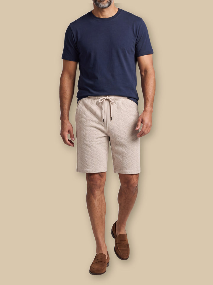 Lucian summer shorts in Sand, worn by a model on a warm sand studio background - Gentlemens Manor