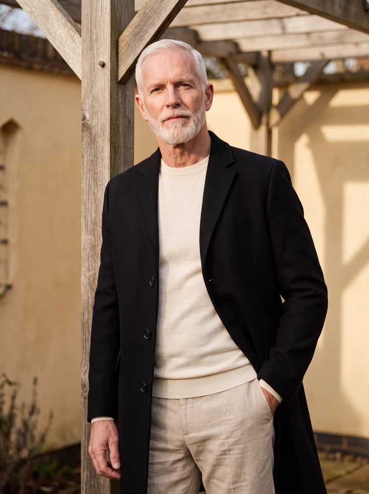 Oliver coat in Black, worn by a model in a Mediterranean setting - Gentlemens Manor lifestyle