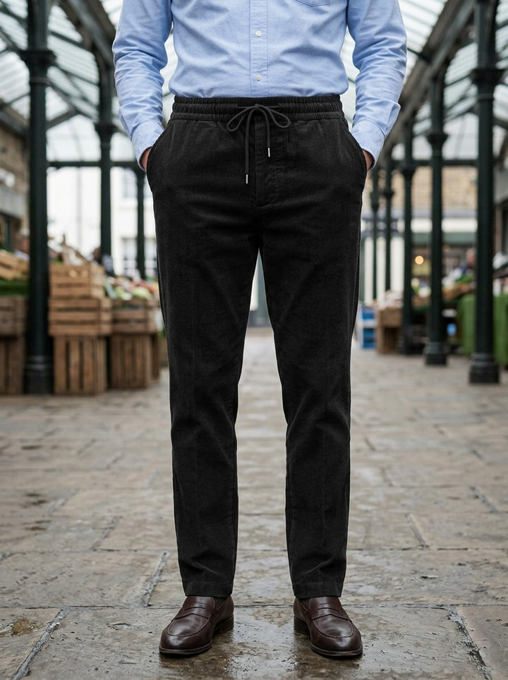 Ormsby corduroy drawstring tapered pants in Black, lifestyle in a covered market hall, Gentlemens Manor