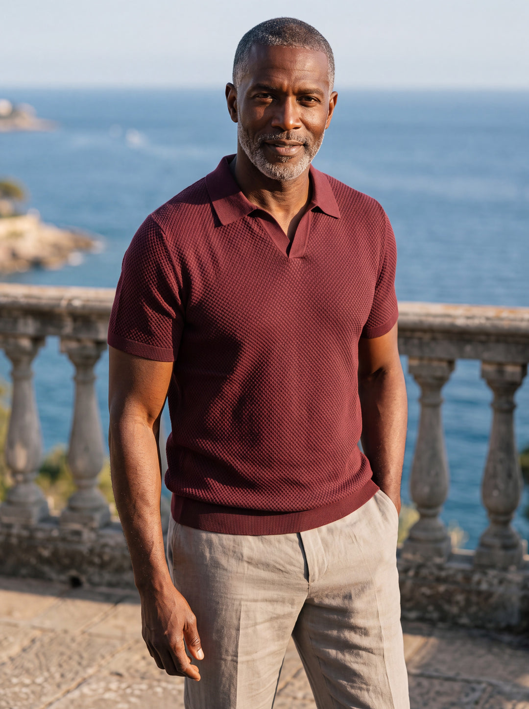 Oswald Men polo shirt in burgundy, worn by a model on a Mediterranean terrace - Gentlemens Manor lifestyle