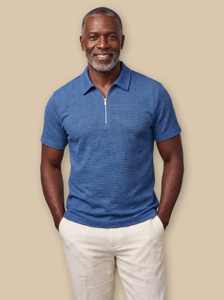 Parker polo shirt in Blue, worn by a model on a warm sand studio background - Gentlemens Manor