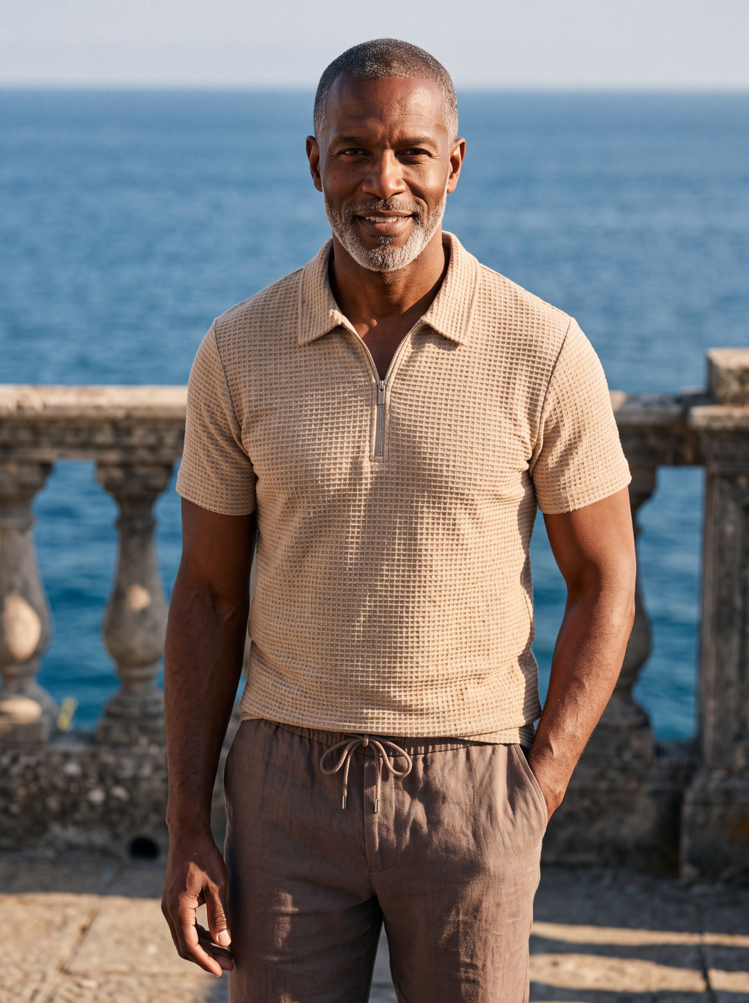 Parker Men polo shirt in sand, worn by a model on a Mediterranean terrace - Gentlemens Manor lifestyle