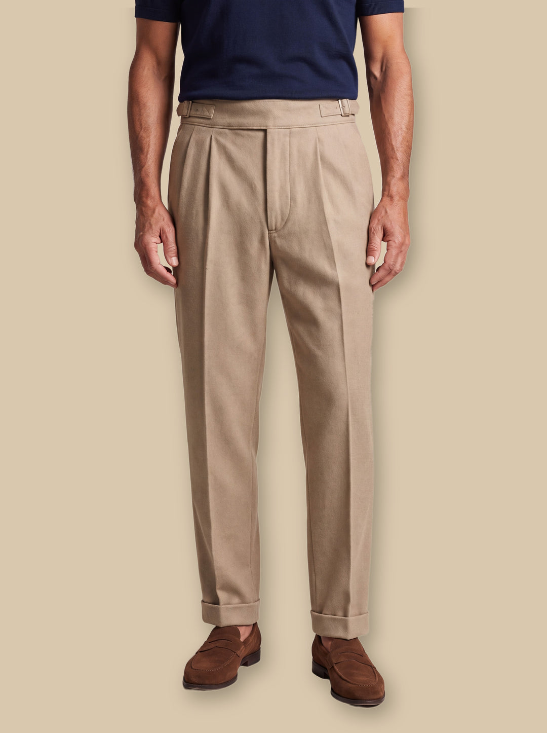 Reuben trousers in Sand, worn by a model on a warm sand studio background - Gentlemens Manor