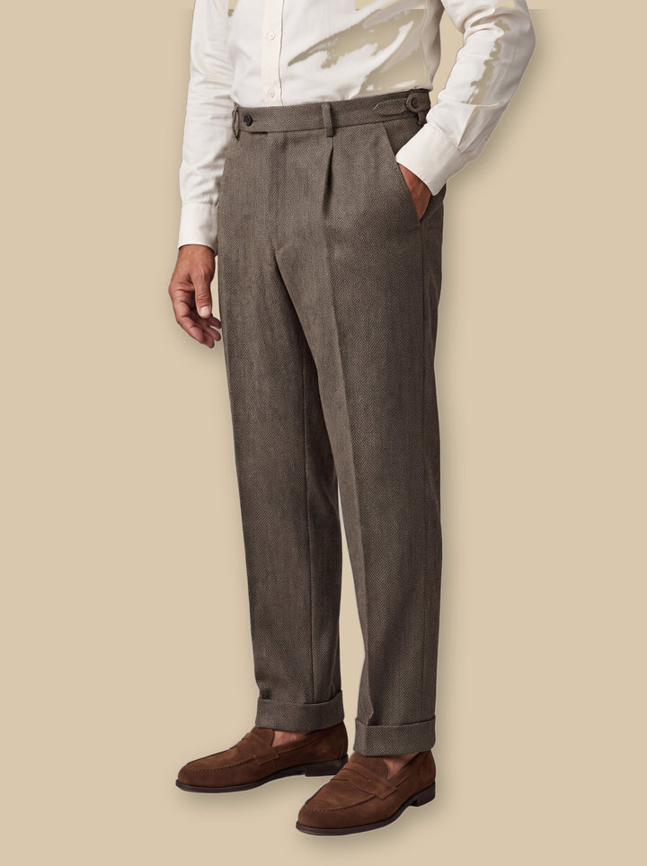 Rex dress trousers in Brown, worn by a model on a warm sand studio background - Gentlemens Manor