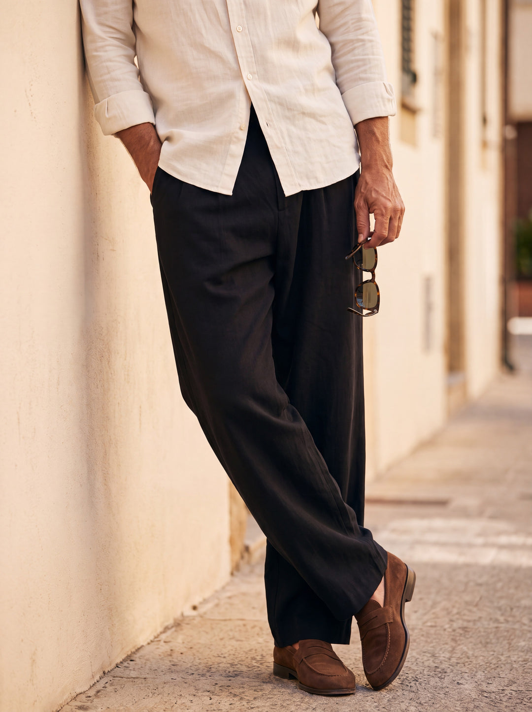 Riley Men trousers in black, worn by a model on a Mediterranean terrace - Gentlemens Manor lifestyle
