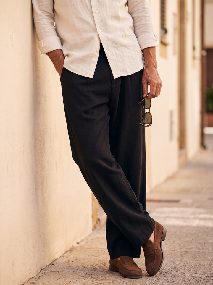 Riley Men trousers in black, worn by a model on a Mediterranean terrace - Gentlemens Manor lifestyle