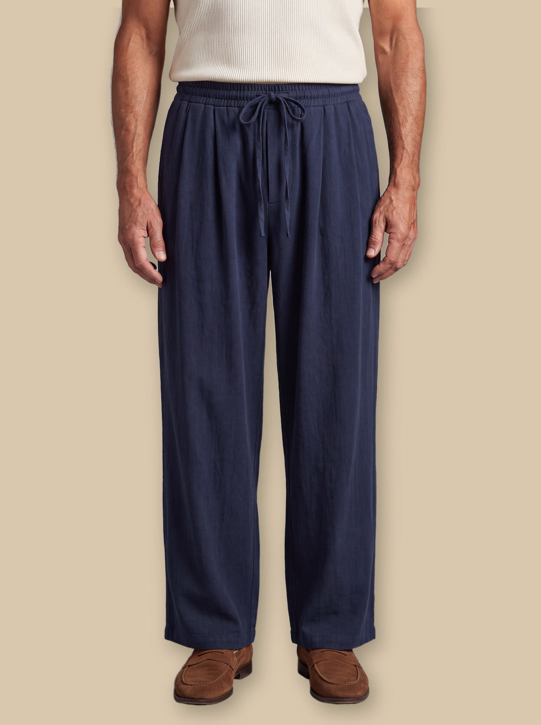 Riley trousers in Navy, worn by a model on a warm sand studio background - Gentlemens Manor