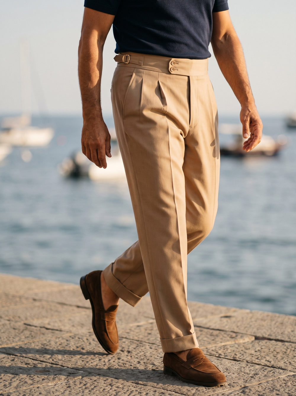 Roman trousers in Beige, worn by a model on a sunlit stone promenade - Gentlemens Manor lifestyle