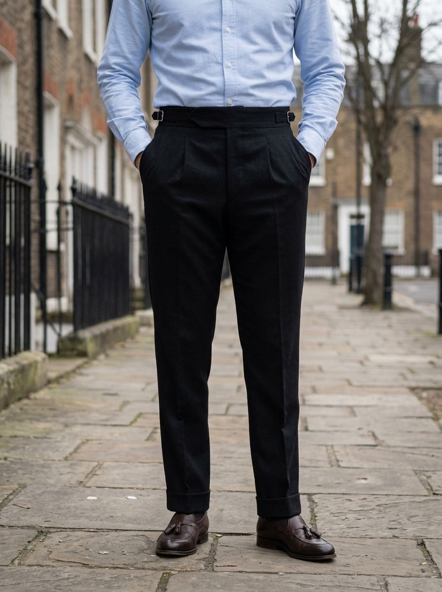 Rupert turn up cuff pleated trousers in Black, lifestyle on a street of brick row houses, Gentlemens Manor