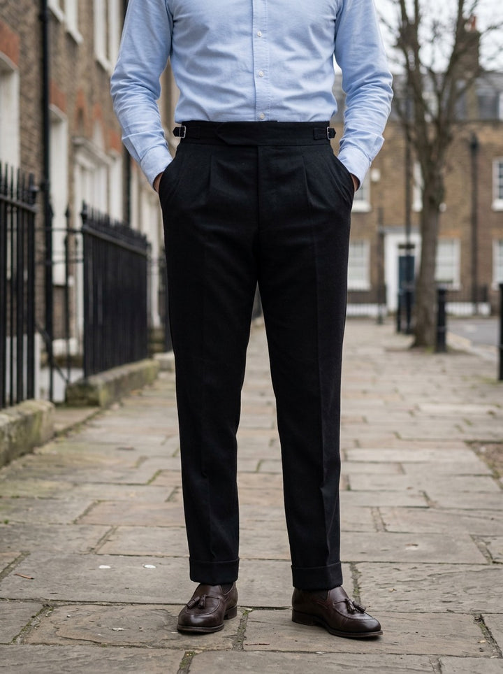 Rupert turn up cuff pleated trousers in Black, lifestyle on a street of brick row houses, Gentlemens Manor