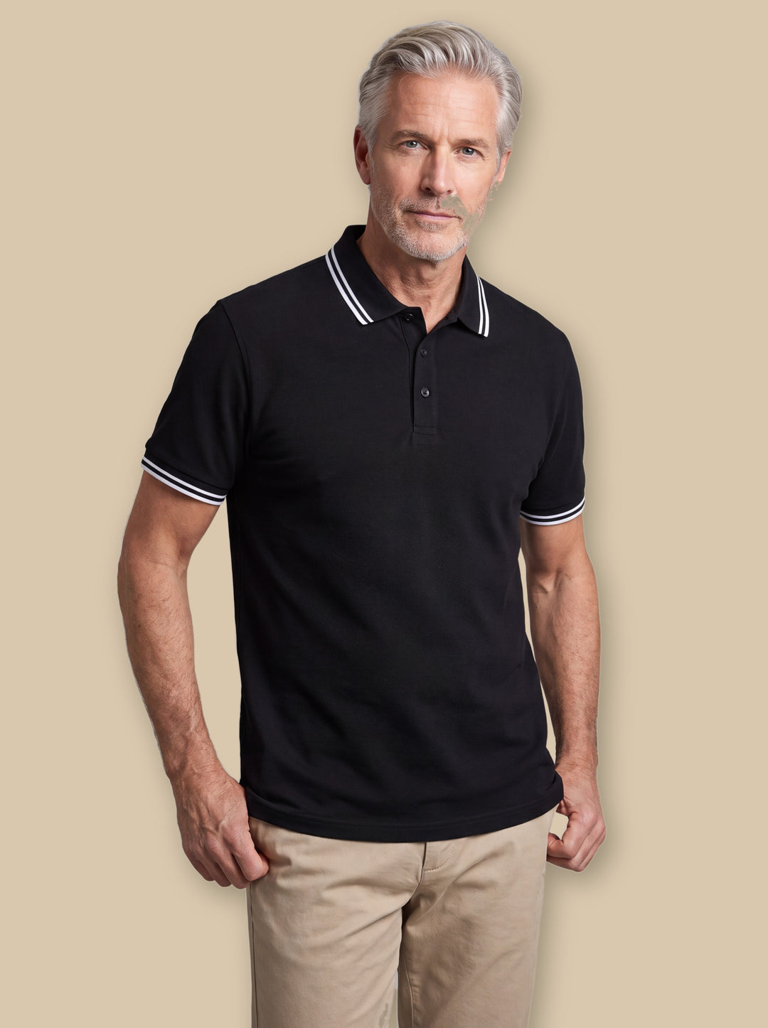 Walter polo shirt in Black, worn by a model on a warm sand studio background - Gentlemens Manor