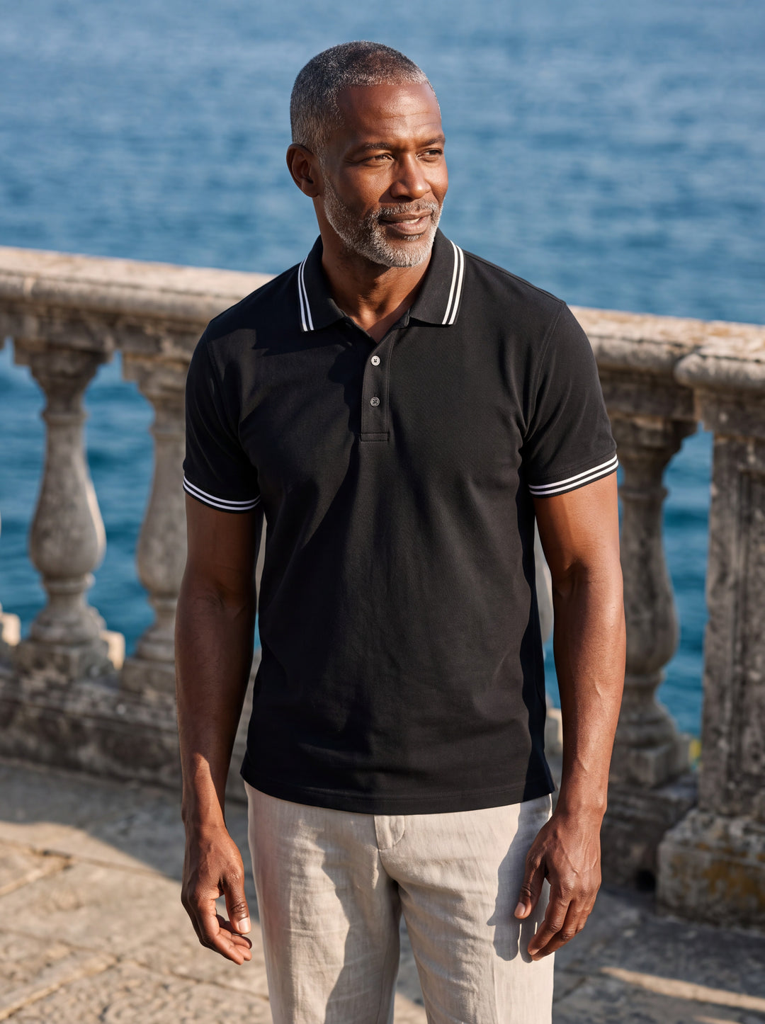 Walter Men polo shirt in black, worn by a model on a Mediterranean terrace - Gentlemens Manor lifestyle