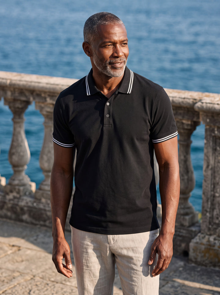 Walter Men polo shirt in black, worn by a model on a Mediterranean terrace - Gentlemens Manor lifestyle